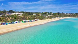 Una platja amb aigües turqueses cristal·lines i una filera de cabanes de bany multicolorades al llarg de la riba.