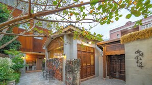A traditional courtyard with stone flooring, wooden furniture, and a thatched roof structure. - Komorebi Souseki (Tainan)
