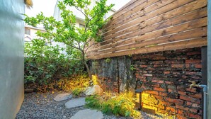 A garden area with a brick wall, wooden fence, and stone steps. - Komorebi Souseki (Tainan)