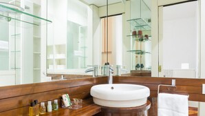 Un baño moderno con tocador de madera, un lavabo blanco y un espejo grande.