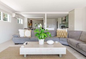 A modern living room with a grey sofa, a coffee table, and a potted plant.