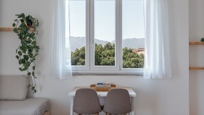 Una stanza con un letto, una scrivania con due sedie, una finestra con tende e una pianta in vaso.