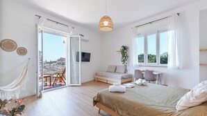 Una camera da letto moderna con un letto, una scrivania, una sedia e un balcone con vista.