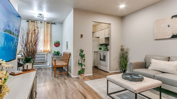 A modern living room with a sofa, ottoman, and a dining area with a chair and table.