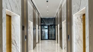Un corridoio moderno con pareti in marmo, pavimento lucido e ingresso per ascensore in vetro.