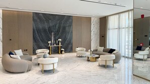 Un soggiorno moderno con morbidi posti a sedere, pavimento in marmo e una grande parete con motivo decorativo.