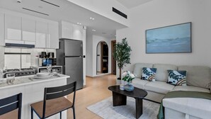Una cucina moderna con mobili bianchi, un'isola centrale e un'area pranzo con sedie.