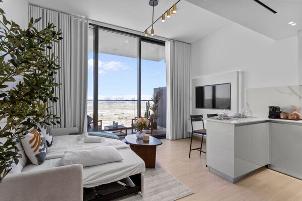 Une chambre dâhĂŽtel moderne dotĂ©e dâune grande fenĂȘtre, dâun lit, dâun petit coin repas et dâun tĂ©lĂ©viseur.