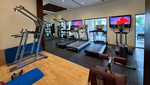 Ein Fitnessraum mit Laufbändern, Crosstrainern und Gewichtsbänken.