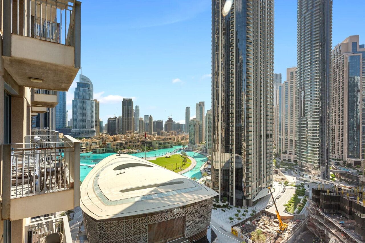 A high-rise building with a view of a cityscape and a large, modern building with a unique roof design.