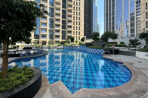 Una piscina con diseño de cuadros, rodeada de vegetación y edificios modernos.