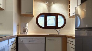 A compact kitchen with white cabinetry, a built-in dishwasher, a coffee maker, and a stainless steel refrigerator. - Spacious T3 for 6 near slopes, comfortable, pets allowed (Les Orres)
