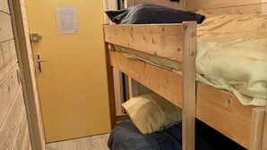 Ein Schlafraum mit Etagenbetten, einem Holzrahmen, einer gelben Tür und Holzboden.