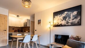 Ein modernes Wohnzimmer mit Fernseher, Sofa und Essbereich.