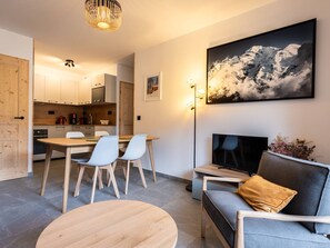 A modern living room with a TV, sofa, and dining area. - New T2 Apartment with Balcony in Valmorel (Valmorel)