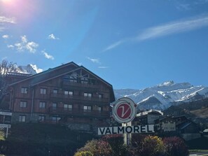 A wooden building with a sign reading "VALMOREL" and a circular sign with a red 'V' in front. - New T2 Apartment with Balcony in Valmorel (Valmorel)
