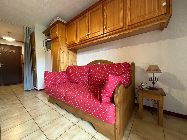 A cozy room with a wooden sofa, a small table with a lamp, and a clock.