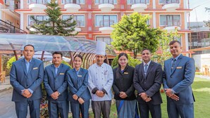 A group of people standing in front of a building with multiple balconies and a glass facade. - Temple Himalaya Hotel & Spa (Pokhara)