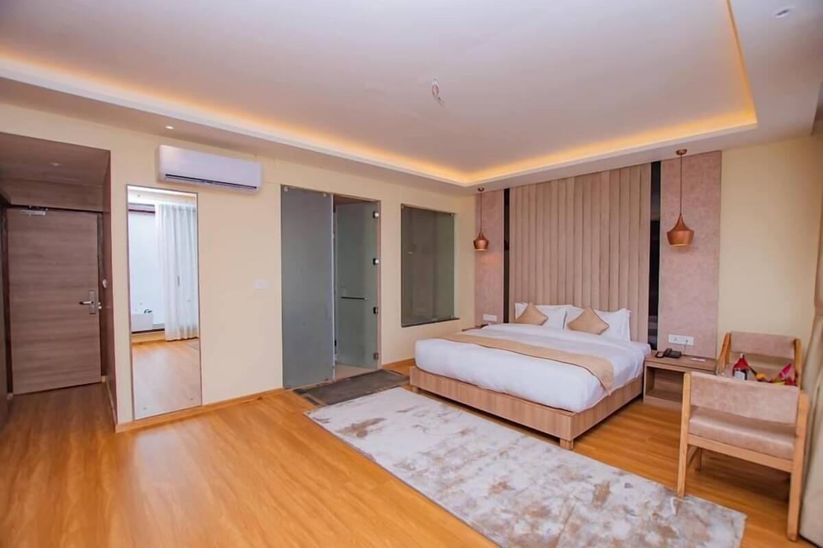 A modern bedroom with a large bed, a wooden floor, and a ceiling with recessed lighting.