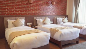 A hotel room with two beds, a brick wall, and a wooden headboard. - Temple Himalaya Hotel & Spa (Pokhara)