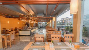 A restaurant with wooden furniture, a bar area, and large windows offering a view of buildings and trees. - Temple Himalaya Hotel & Spa (Pokhara)