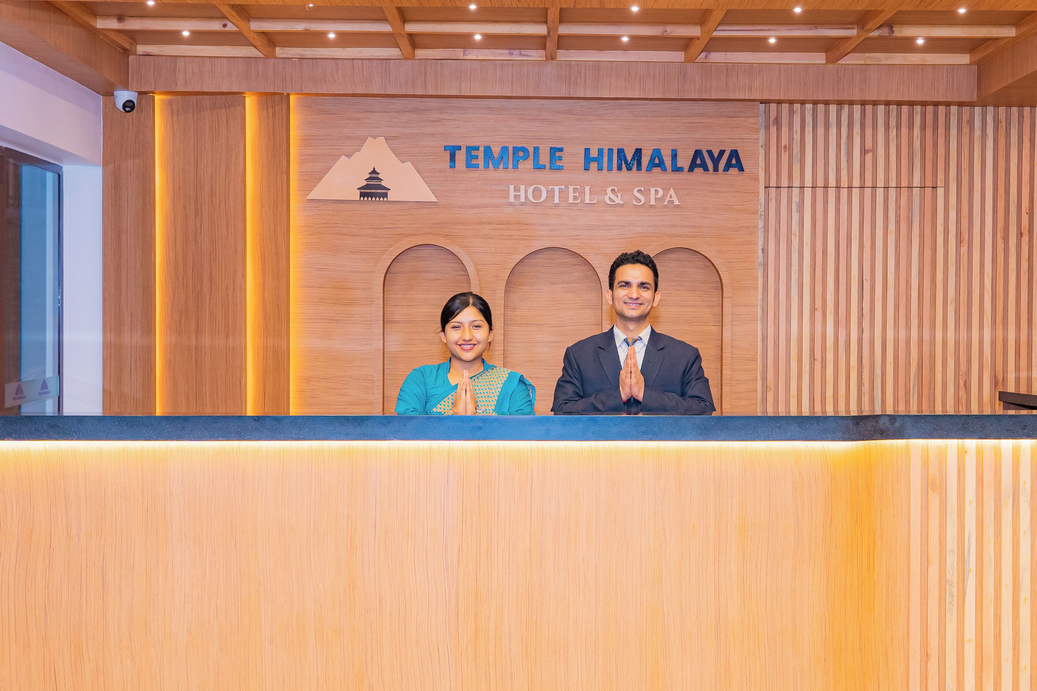 Een houten receptiebalie bij Hotel & Spa Temple Himalaya, met een bord erboven.
