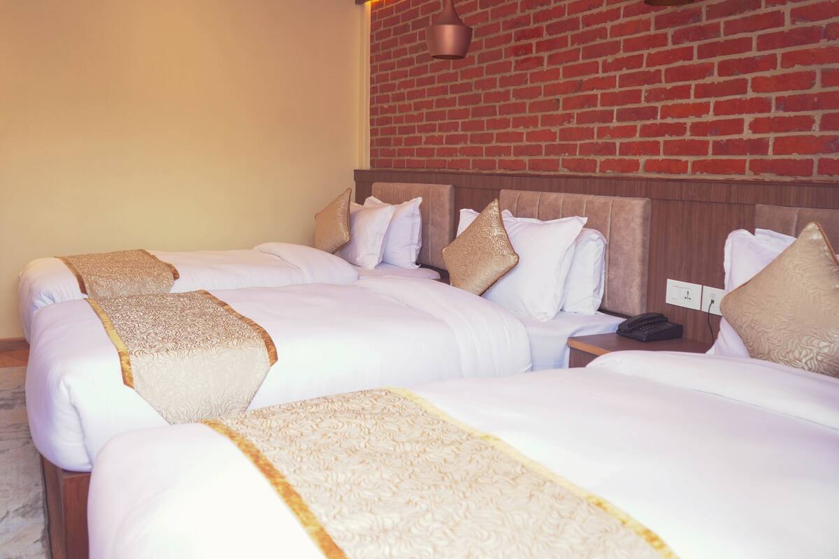 A hotel room with two beds, a brick wall, and a wooden headboard.