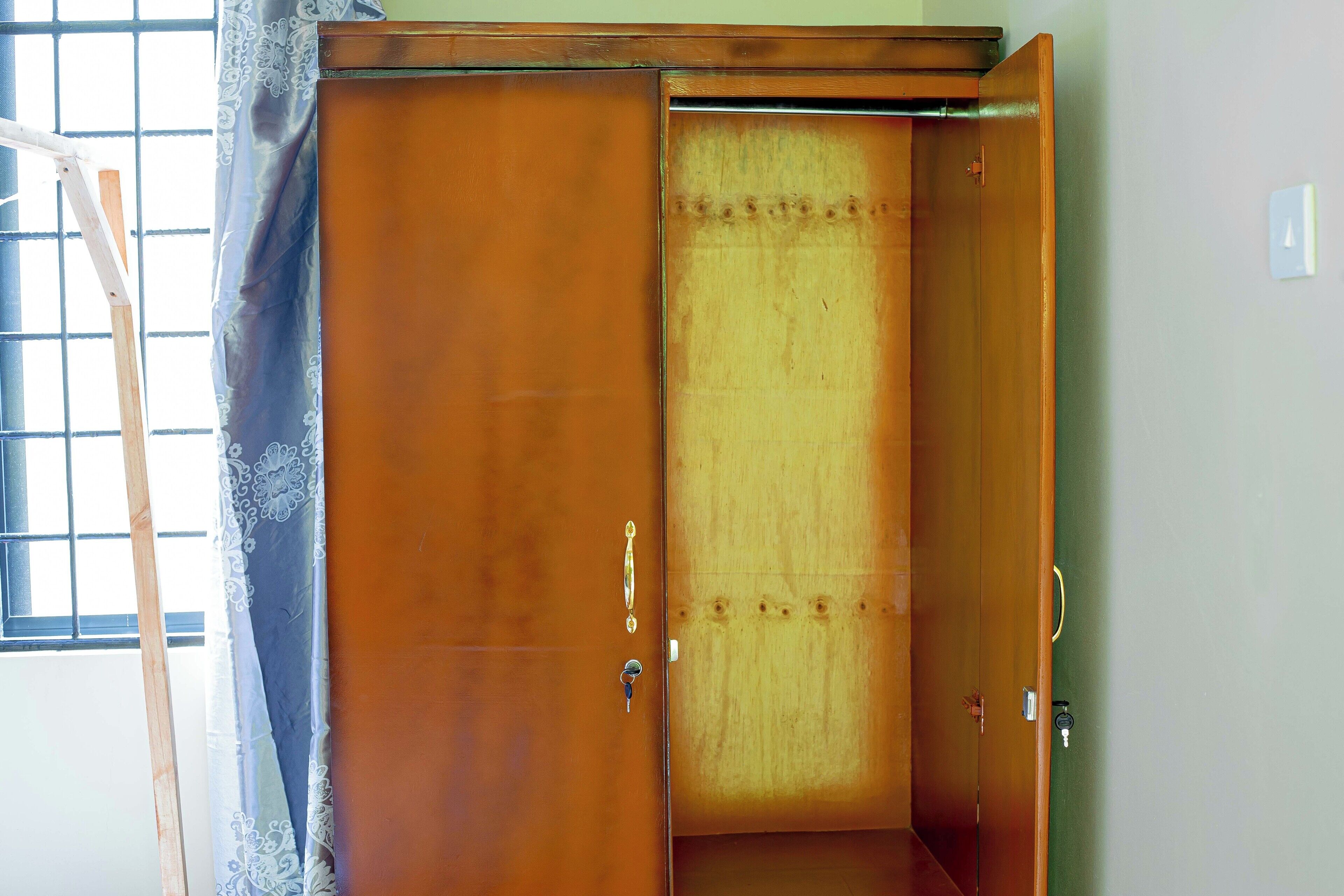Un armario de madera con puerta corredera, un ojo de cerradura y un estante pequeño.