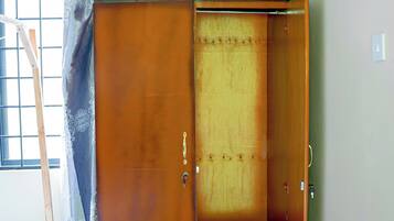 Un armario de madera con puerta corredera, un ojo de cerradura y un estante pequeño.