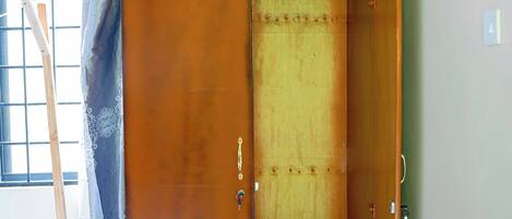 Un armario de madera con puerta corredera, un ojo de cerradura y un estante pequeño.