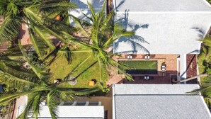 An aerial view of a residential area with a swimming pool, a patio with seating, and surrounding palm trees. - Elegant Boutique Hotel Luangpraban (Luang Prabang)