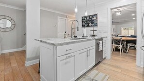 Een moderne keuken met witte kasten, een marmeren aanrechtblad en hanglampen.