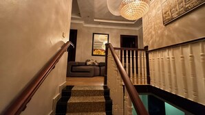 Un escalier avec une rampe en bois, un lustre et une œuvre d’art encadrée accrochée au mur.