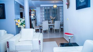 Un salon moderne avec un canapé blanc, un coin repas agrémenté d’un lustre et un évier rouge.
