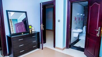 A room with a dark wooden dresser, a mirror, and an open door leading to a bathroom with a toilet and sink.