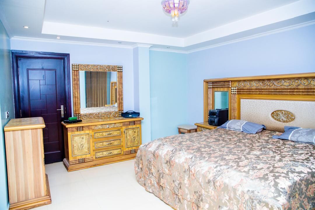 A bedroom with a large bed, a dresser, a mirror, and a nightstand.