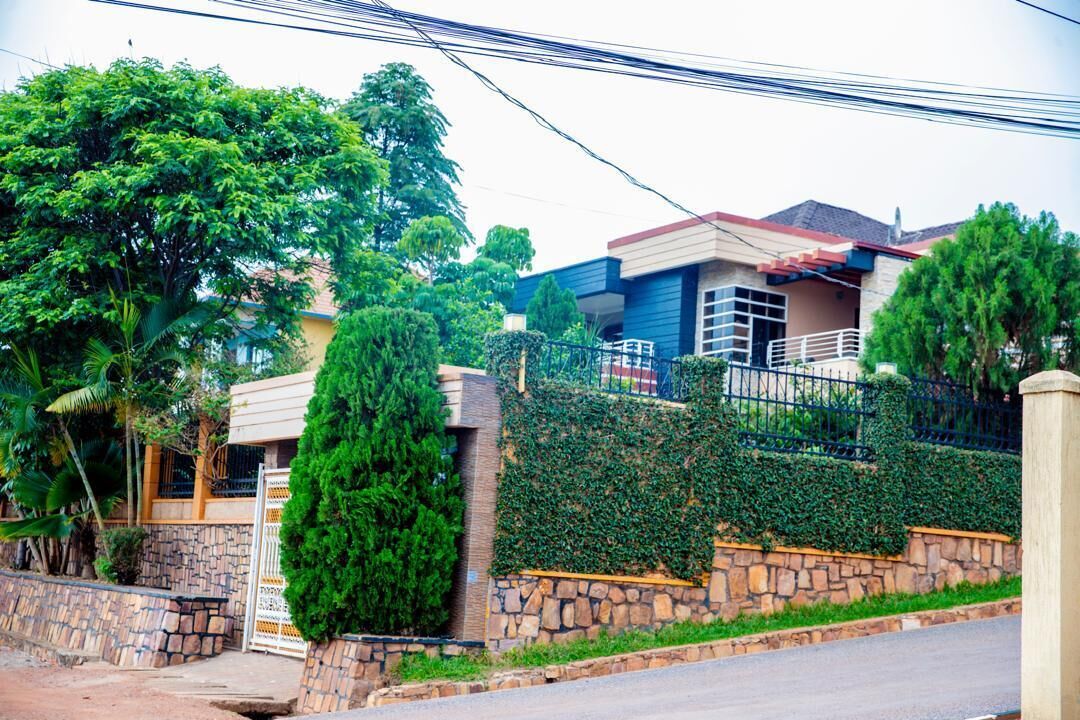 Une maison d’habitation avec un mur en pierre, un portail en métal et un jardin bien entretenu.