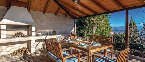 An outdoor patio with a stone floor, wooden furniture, and a view of the landscape.