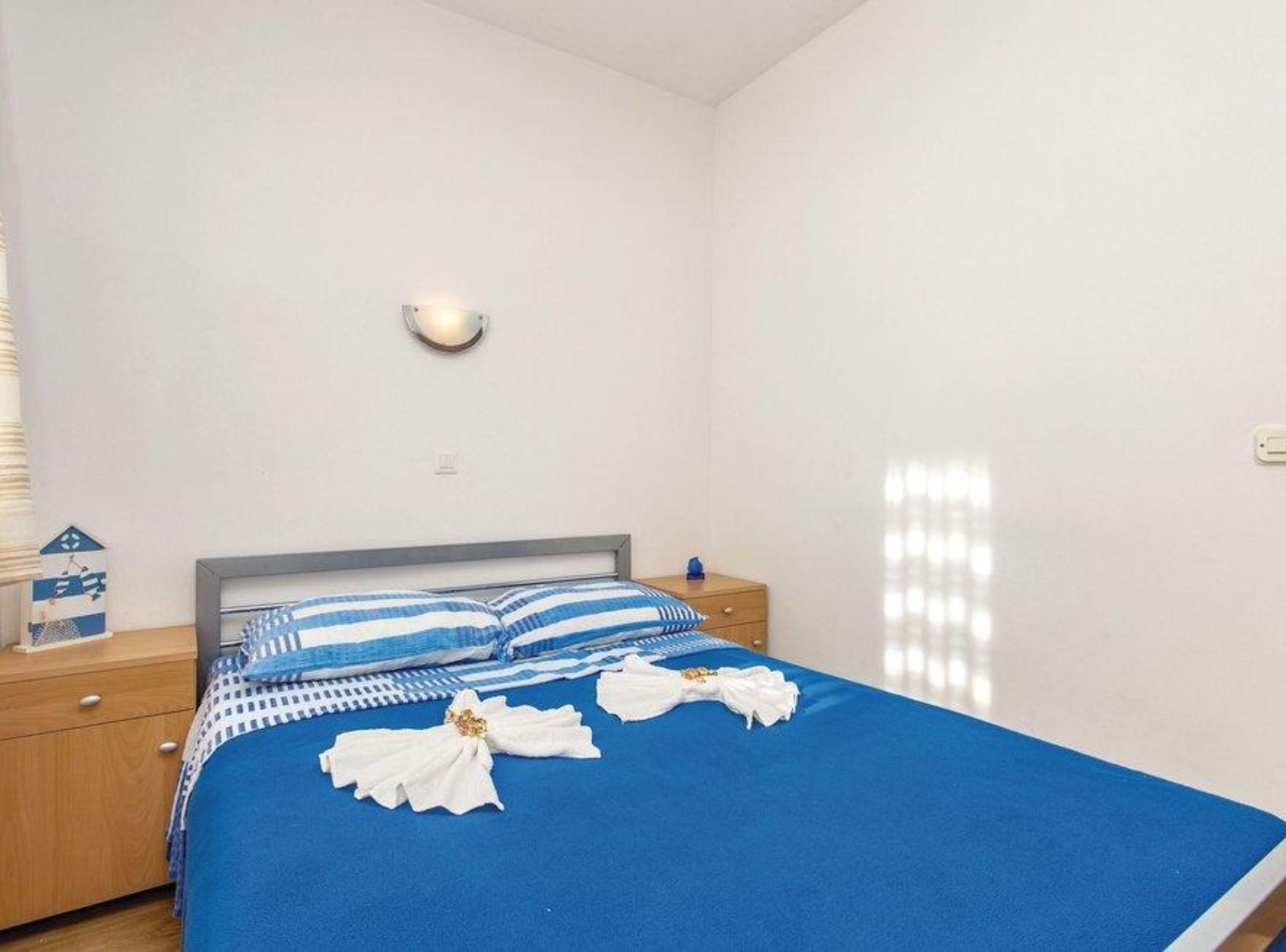 Ein Schlafzimmer mit einem Bett, einem Nachttisch, einer Wandleuchte und einer kleinen Dekoration auf dem Nachttisch.