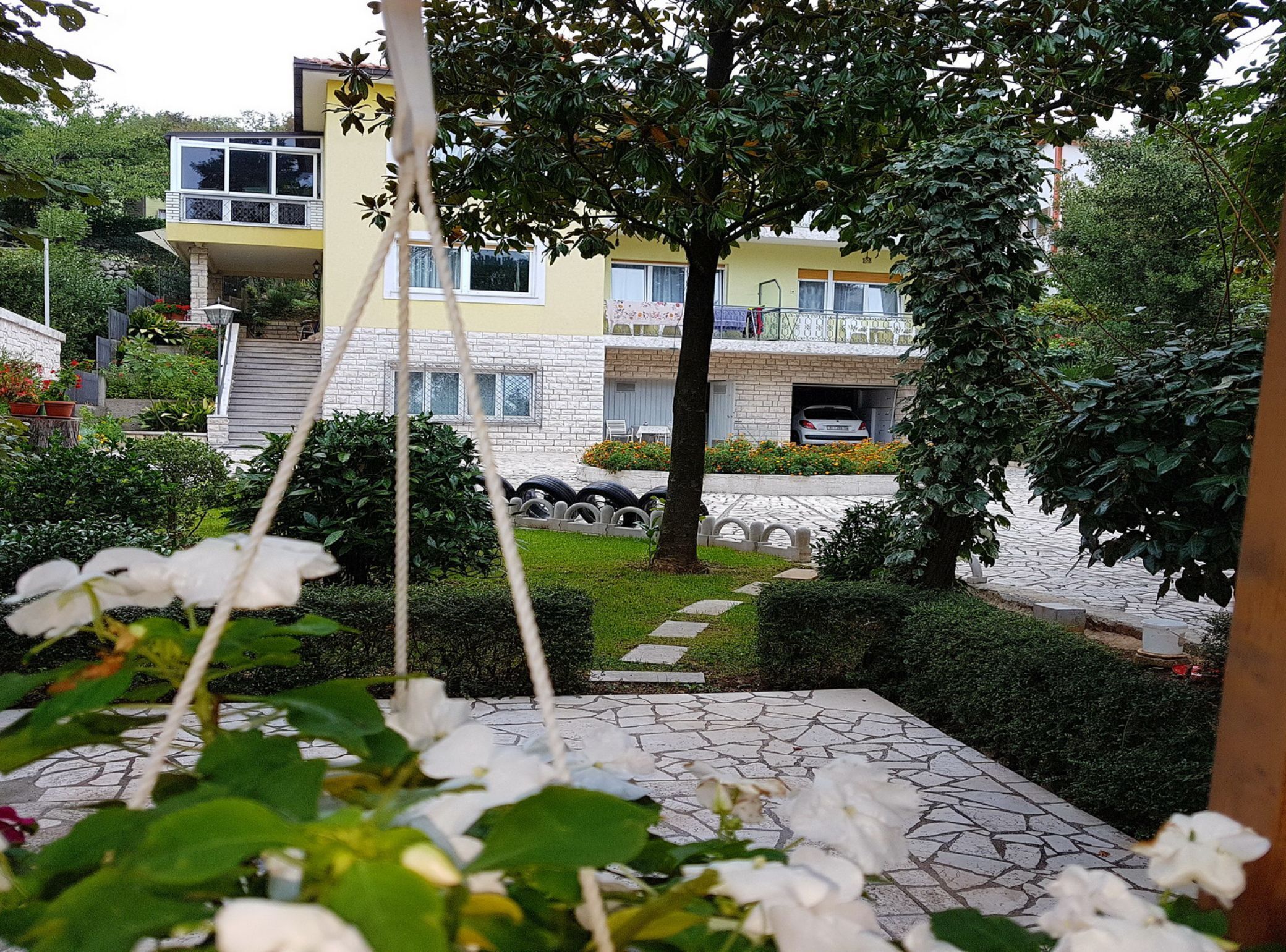Un edificio residencial de dos pisos, con un balcón y una entrada de acceso a un coche estacionado.