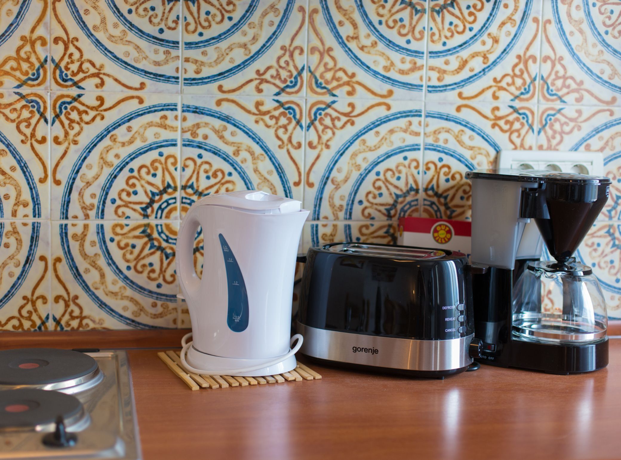 A kitchen with a coffee maker, toaster, and kettle on a wooden countertop.