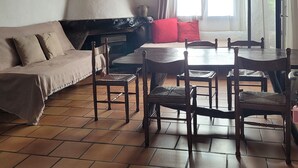 Un salon chaleureux avec un plafond en bois, un canapé, une table à manger avec des chaises et une fenêtre avec des rideaux.