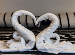 A towel arranged in a heart shape on a striped sofa.