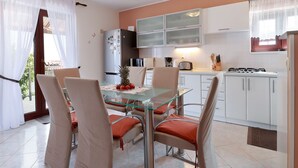 A modern kitchen with white cabinets, a glass dining table, and a stainless steel stove. - Sunny Holiday Home With Terrace (Lovran)