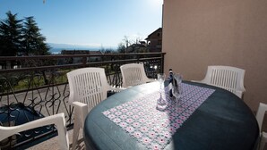 A balcony with a table set for two, overlooking a scenic view of the sea and mountains. - Cozy Icici Apartment With Sea View (Opatija)