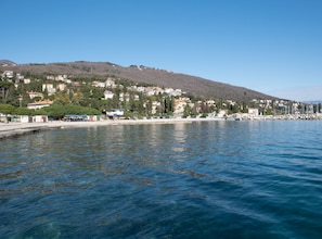 A coastal town with buildings along the waterfront, a clear sky, and calm water.
