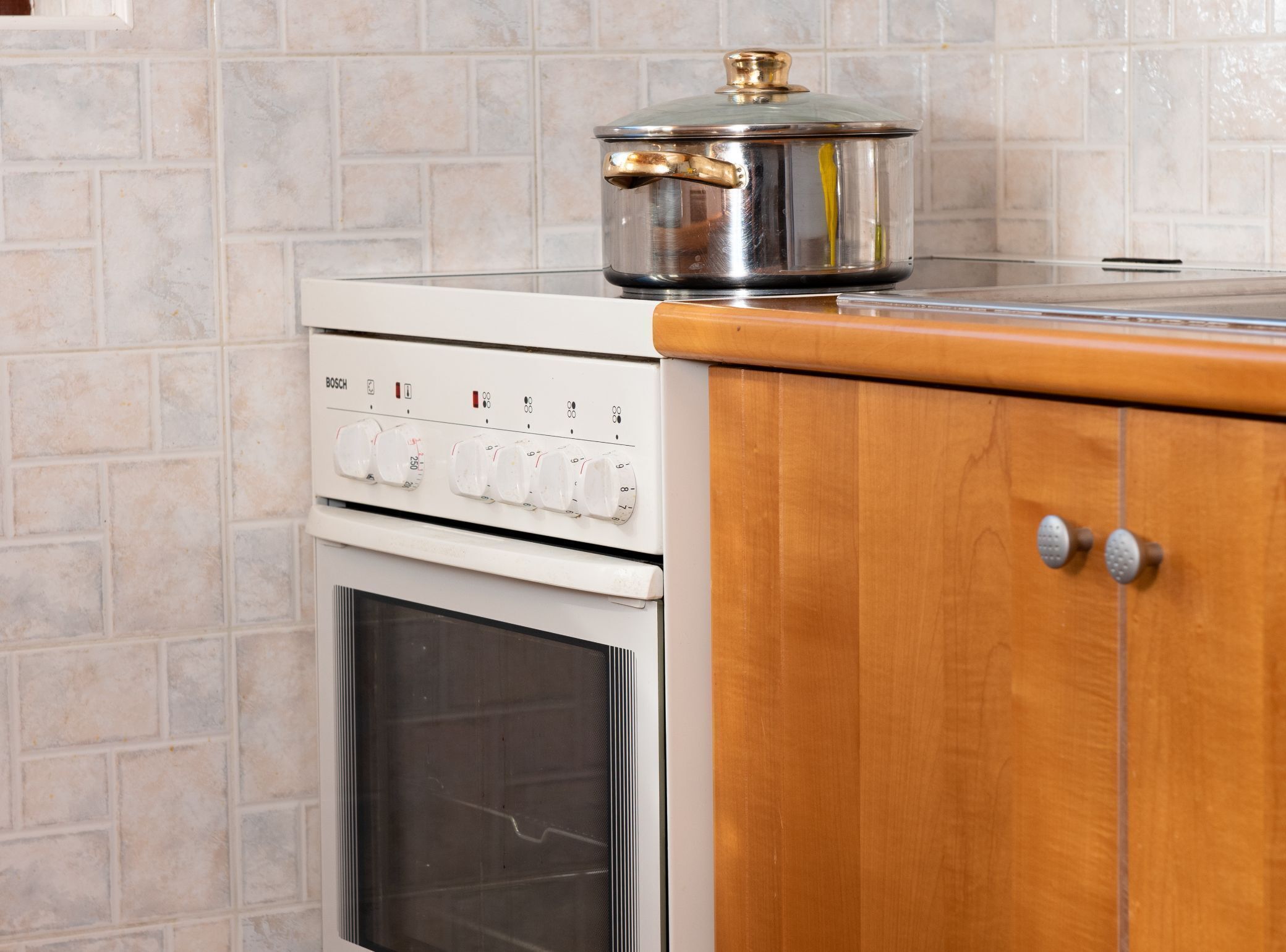 A kitchen with a Bosch oven and a pot on top.