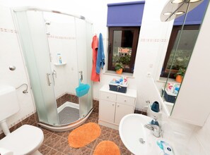 Un bagno moderno con cabina doccia in vetro, lavandino bianco e mobile vanità con specchio.