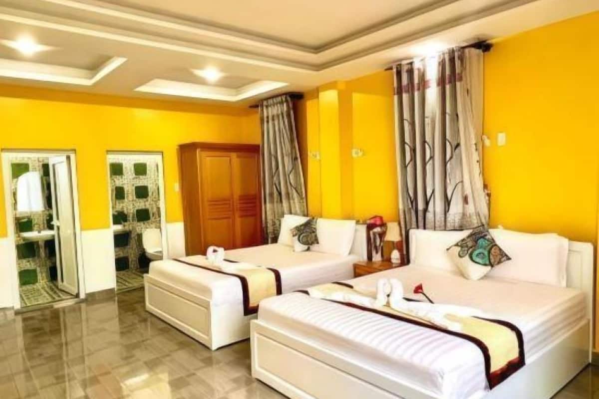 A hotel room with two beds, a wardrobe, and a bathroom with a mirror and sink.