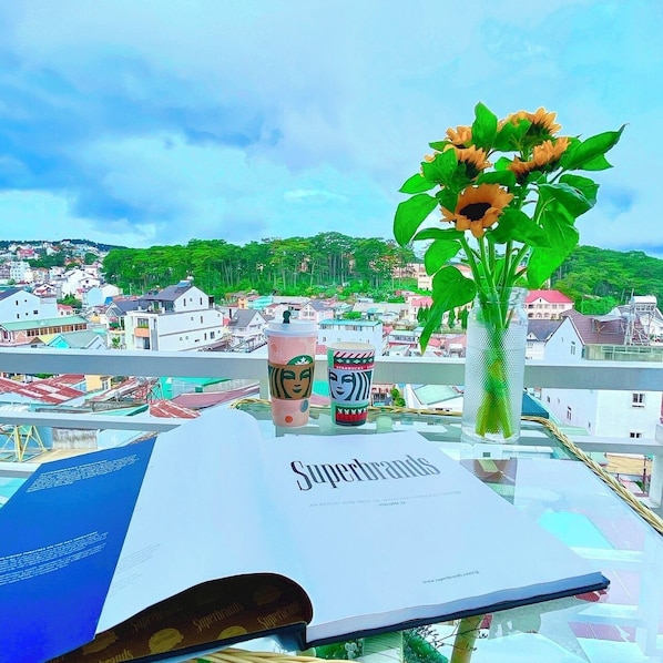 A book titled 'Superbrands' on a table with a glass vase containing sunflowers, two Starbucks cups, and a view of a cityscape.